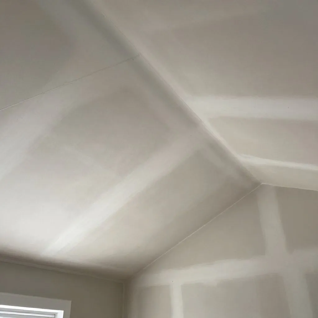 Completed drywall ceiling installation in vaulted ceiling with clean seam work