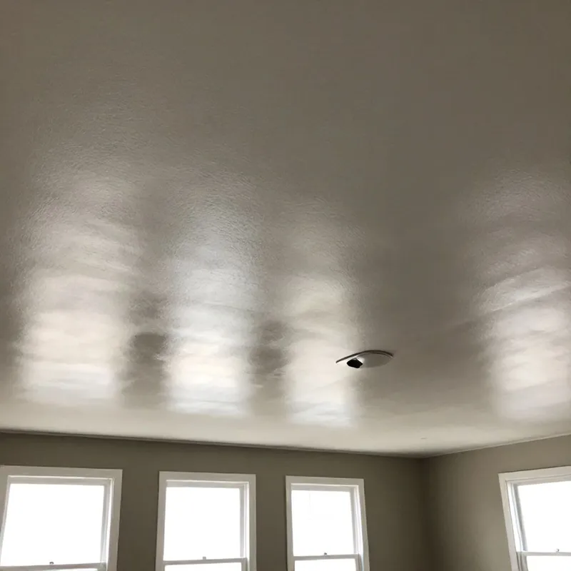 Professional popcorn ceiling removal in progress using safe wet scraping method